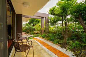 a patio with a table and chairs and a garden at Peace Branch in Yonabaru