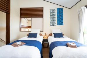 two beds in a room with blue and white at Peace Branch in Yonabaru