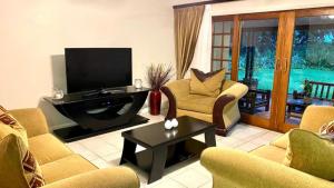 a living room with couches and a flat screen tv at Fairways 5, Zimbali Estate by Euphoric Leisure in Ballito