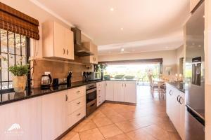 a large kitchen with white cabinets and a large window at Aleah, Cathkin Estates by Euphoric Leisure in Champagne Valley