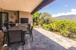 a patio with a table and chairs and a television at Aleah, Cathkin Estates by Euphoric Leisure in Champagne Valley