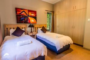 a bedroom with two beds and a painting on the wall at Aleah, Cathkin Estates by Euphoric Leisure in Champagne Valley