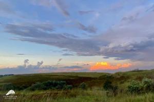 a sunset in a field with a cloudy sky at Aleah, Cathkin Estates by Euphoric Leisure in Champagne Valley