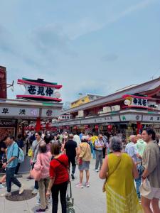 a crowd of people walking through a crowd of shops at househotel上野 入谷 in Tokyo