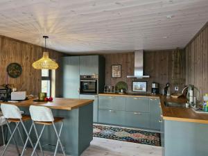 a kitchen with blue cabinets and a counter with stools at New Mountain Cabin With Views Over Eggedal in Eggedal