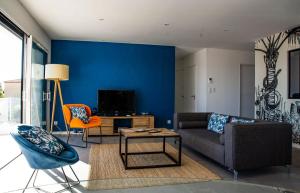 ein Wohnzimmer mit einer blauen Wand, einem Sofa und einem Tisch in der Unterkunft Villa With Panoramic Views Of Thau Lagoon in Bouzigues