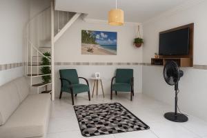 a living room with two chairs and a tv at Encanto Guarapari in Guarapari