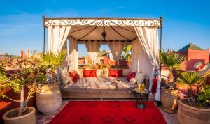 a bedroom with a canopy bed with a red rug at Riad Eden in Marrakesh