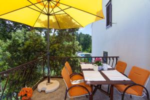 a table and chairs with a yellow umbrella on a balcony at Apartments Matijasevic in Korčula