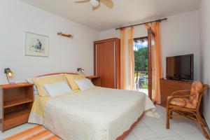 a bedroom with a bed and a television and a chair at Apartments Matijasevic in Korčula
