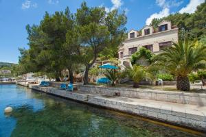 a house on the side of a river with trees at Apartments Matijasevic in Korčula