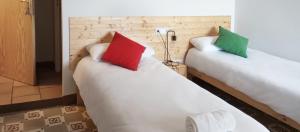 two beds with red and green pillows in a room at Santuari de Santa Maria de Montgrony in Gombreny