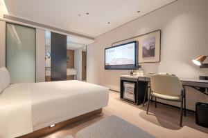a bedroom with a bed and a desk and a television at Atour Hotel Shenzhen Nanshan West Lizhi Valley Industrial Park in Shenzhen +41 photos