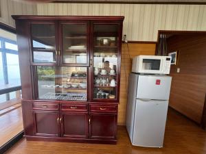 呉市にある民泊大浦崎荘のキッチンにある電子レンジと冷蔵庫付きのキャビネット