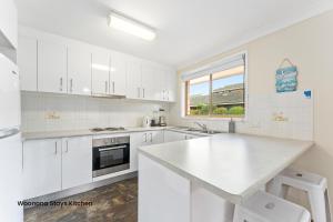 a kitchen with white cabinets and a white counter top at Woonona Stays in Woonona +26 photos