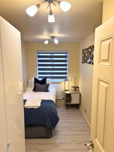 ein Schlafzimmer mit einem Bett mit blauen Kissen und einem Fenster in der Unterkunft Aisiki Stays Apartments at Colindale, Ground Floor, 2-Bedroom & 1-Bathroom, Pet-Friendly, with Free Wi-Fi and Parking Space in Colindale