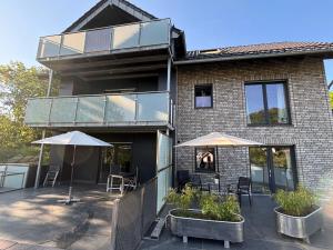 a house with two umbrellas and a patio at Appartement am Hostertberg 1 in Simmerath