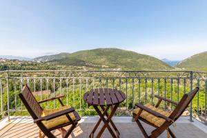 two chairs and a table on a balcony with mountains at Odyssey's Palace - Escape in Mythical Ithaca in Platithriás