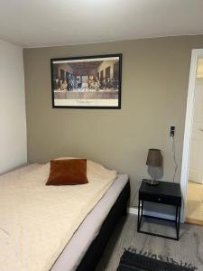 a bedroom with a bed and a picture on the wall at To værelser med dobbeltsenge tæt på E45 og banegården i Rødekro Værelserne deler bad Kælderværelser med egen indgang in Rødekro