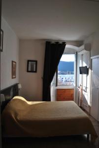 a bedroom with a bed and a large window at Hotel Restaurant L'Europe in Saint-Florent
