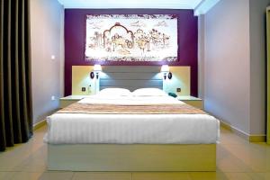 a bedroom with a large bed with a painting above it at Tilko Jaffna City Hotel in Jaffna +15 photos