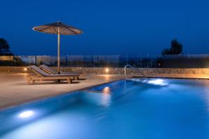a swimming pool with an umbrella and a chair and a table at Villa Vasaltis & Selestitis in Gennadi