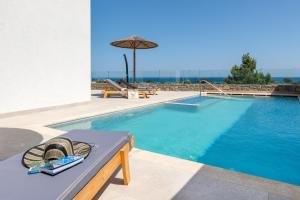 a swimming pool with a bench and an umbrella at Villa Vasaltis & Selestitis in Gennadi