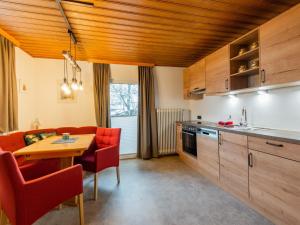 a kitchen and dining room with a table and red chairs at Modern Apartment in Kitzbuhel near Ski Area in Kitzbühel