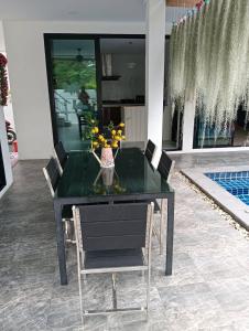 a dining room table with chairs and a vase of flowers at Lemony Pool Villa - Hua Hin in Ban Thap Tai (1)