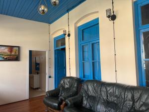 a leather couch in a living room with blue doors at Guesthouse Anaberika in Velistsʼikhe