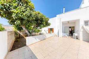 a patio with a tree next to a white building at Casa Saulle - Costruzione Tipica in Felline