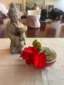 a candle and a small statue next to a bowl of red flowers at Fenix Villa in Noicattaro