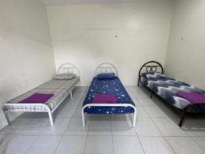 two beds in a room with purple and blue sheets at Bilik 3 Katil Single Aircond Pekan in Pekan +21 photos