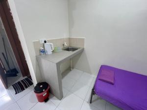 a small bathroom with a sink and a purple stool at Bilik 3 Katil Single Aircond Pekan in Pekan