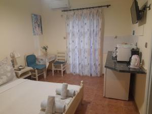 a room with two beds and a kitchen and a table at Studios Eftichia in Fourni Ikarias