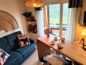 salon z niebieską kanapą i drewnianym stołem w obiekcie Petit cocon plein sud vue montagnes Lesclesdenicole w mieście Barcelonnette