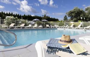 a hat sitting on a chair next to a swimming pool at Cottage 4 personnes in Mirepoix