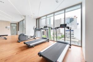 un gimnasio con máquinas cardiovasculares y ventanas grandes en The Rich Grand Residence Sukhumvit, en Bangkok