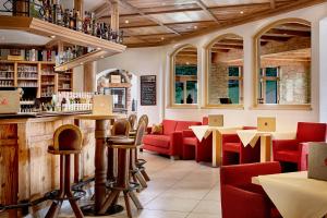 a restaurant with red chairs and a bar at Hotel Kroneck in Kirchberg in Tirol