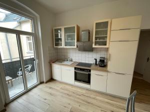 a kitchen with white cabinets and a large window at Schönes Apartment mit Infrarot Sauna und Balkon "Afrika" in Plauen