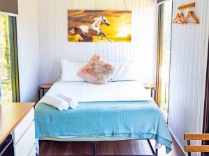 a bedroom with a bed with a painting of a horse at Guanaba Farm by Tiny Away in Eagle Heights