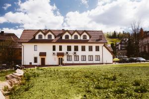een groot wit huis met een grasveld ervoor bij Orange Pokoje in Karpacz