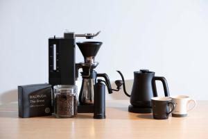 a coffee maker and cups on a table at マイグレテラス in Ito