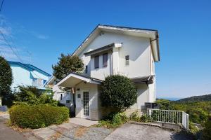 a white house with a fence in front of it at マイグレテラス in Ito