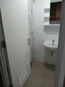 a white bathroom with a sink and a mirror at Skylounge Makassar Apartment in Manda