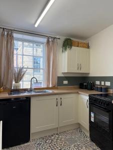 a kitchen with white cabinets and a sink and a window at Bow Alley Lodge in Alnwick +17 photos