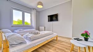 two beds in a room with a table and a tv at Waryńskiego, Sun & Snow in Szklarska Poręba +3 photos