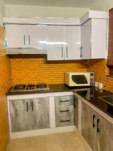 a kitchen with white cabinets and a microwave at Royal Serviced Cottages in Murree