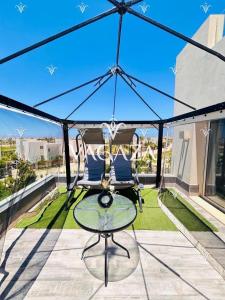 a patio with two chairs and a glass table at For Rent Luxurious 3-Bedroom Chalet at Hacienda Bay, North Coast, Egypt in El Alamein +24 photos