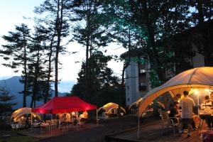 a group of people sitting at tables under umbrellas at Kitashiga Holiday Inn in Yamanouchi